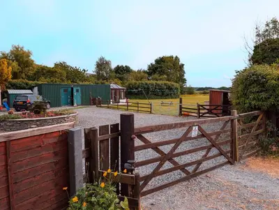 a wooden fence with a gate in a field at Garth Nook Barn in Soutergate