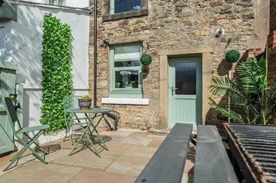 a patio with a table and chairs and a building at Elsie's Cottage in Ribchester
