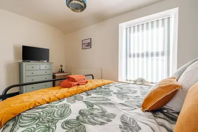 a bedroom with a bed and a tv and a window at Elsie's Cottage in Ribchester