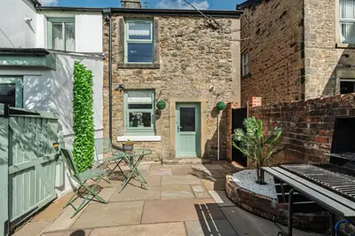 a patio with a table and chairs in front of a building at Elsie's Cottage in Ribchester