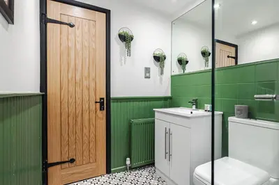 a green bathroom with a toilet and a sink at Elsie's Cottage in Ribchester