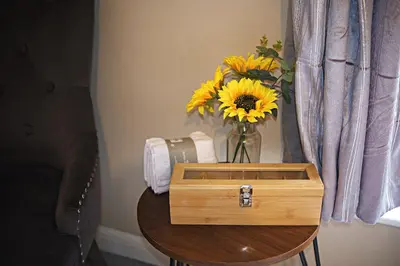 a vase of sunflowers sitting on a table with a box at Thirlmere in Upholland