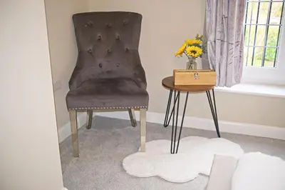 a chair and a table with a vase of flowers at Thirlmere in Upholland