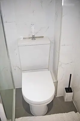 a white toilet in a bathroom with white marble walls at Thirlmere in Upholland