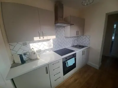 a kitchen with white cabinets and a stove top oven at Heysham Seaside Hideaway in Heysham
