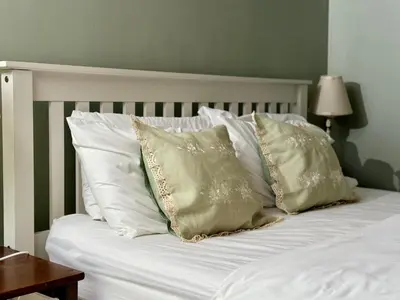 a white bed with white pillows and a green wall at Aesthetic Architect designed Loft in City Centre in Liverpool