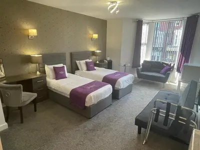 a hotel room with two beds and a chair at Ruskin Hotel in Blackpool