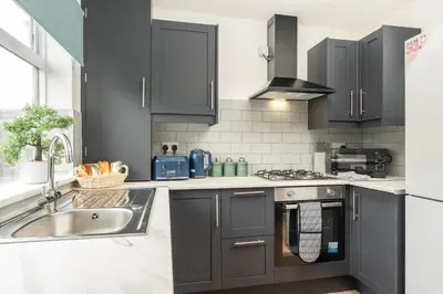 a kitchen with a sink and a stove top oven at Entire 4 Bedroom house in Bootle Liverpool-Ideal for contractors, family and group-Free Parking & Free internet-Sleeps 7 in Litherland