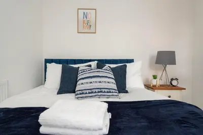 a bed with blue and white sheets and pillows at Entire 4 Bedroom house in Bootle Liverpool-Ideal for contractors, family and group-Free Parking & Free internet-Sleeps 7 in Litherland