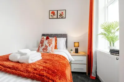a bedroom with a bed with an orange blanket at Entire 4 Bedroom house in Bootle Liverpool-Ideal for contractors, family and group-Free Parking & Free internet-Sleeps 7 in Litherland