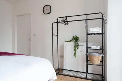 a bedroom with a black shelving unit next to a bed at Entire 4 Bedroom house in Bootle Liverpool-Ideal for contractors, family and group-Free Parking & Free internet-Sleeps 7 in Litherland