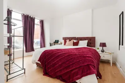a bedroom with a large bed with a red blanket at Entire 4 Bedroom house in Bootle Liverpool-Ideal for contractors, family and group-Free Parking & Free internet-Sleeps 7 in Litherland