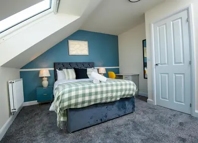 a bedroom with a bed with a blue wall at Luxury 5BDR with City Access, Free Parking and Wi-Fi in Ince-in-Makerfield