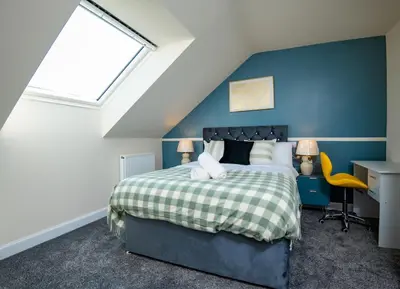 a bedroom with a bed and a blue wall at Luxury 5BDR with City Access, Free Parking and Wi-Fi in Ince-in-Makerfield