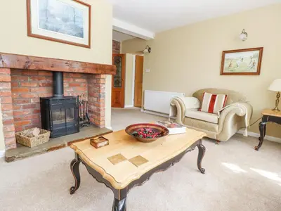 a living room with a fireplace and a table at The Old Coach House in Preston