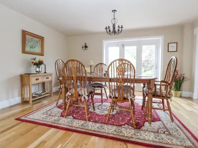 a dining room with a table and chairs on a rug at The Old Coach House in Preston
