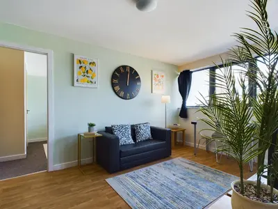 a living room with a couch and a clock on the wall at Group-Friendly City-Centre Flat Wifi, sleeps 4 in Liverpool