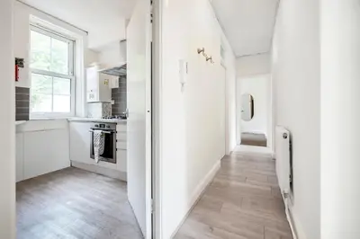 a kitchen with white walls and wooden floors at Modern London stay near Nothing Hill in Hoghton