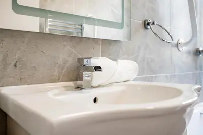 a bathroom with a white sink and a mirror at Modern London stay near Nothing Hill in Hoghton