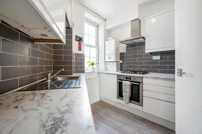 a kitchen with white cabinets and a sink at Modern London stay near Nothing Hill in Hoghton