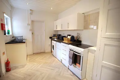 a kitchen with white cabinets and a washer and dryer at Signature Coastal Suites - Two Chic & Stylish Apartments by Parydise Properties in Morecambe