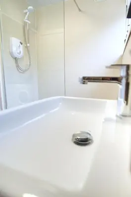 a white bath tub with a shower in a bathroom at Signature Coastal Suites - Two Chic & Stylish Apartments by Parydise Properties in Morecambe