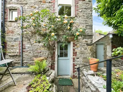 a stone house with a blue door and a tree with flowers at 3 Chapel Square in Lancaster