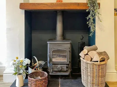 a wood stove in a room with a basket of logs at 3 Chapel Square in Lancaster