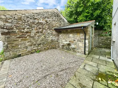 a stone building with a garage next to a stone wall at 3 Chapel Square in Lancaster