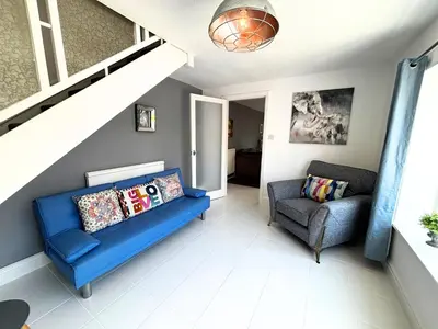 a living room with a blue couch and a chair at Yellow House Cottage in Southport