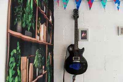 a guitar hanging on a wall next to a wall at Yellow House Cottage in Southport