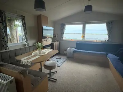 a living room with a table and a blue couch at Lush Lake View in Millom