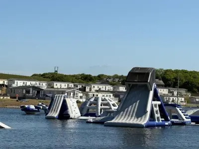 a row of slides in the water with houses at Lush Lake View in Millom