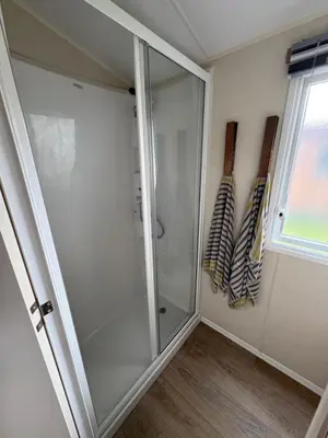 a glass shower in a bathroom with a window at Lush Lake View in Millom