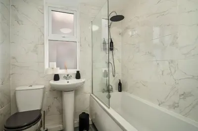 a white bathroom with a sink and a toilet and a shower at Beautiful 3BR Flat near LFC Stadium - Sleeps 8 in Liverpool