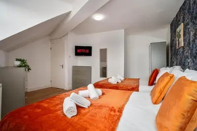 a bedroom with two beds with orange and white sheets at Beautiful 3BR Flat near LFC Stadium - Sleeps 8 in Liverpool
