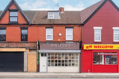 a red building on a street with a store at Beautiful 3BR Flat near LFC Stadium - Sleeps 8 in Liverpool