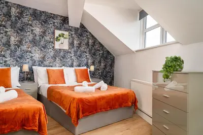 a attic bedroom with two beds and a window at Beautiful 3BR Flat near LFC Stadium - Sleeps 8 in Liverpool