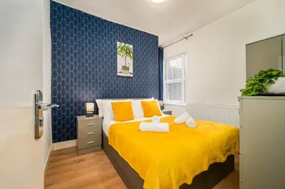 a bedroom with a bed with yellow sheets and orange pillows at Beautiful 3BR Flat near LFC Stadium - Sleeps 8 in Liverpool