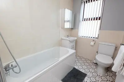 a white bathroom with a tub and a toilet at 3-Bed Coastal Retreat in Waterloo