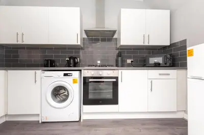 a kitchen with white cabinets and a washer and dryer at 3-Bed Coastal Retreat in Waterloo