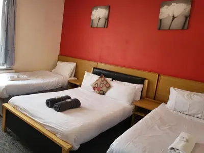 two beds in a room with red walls at Tulip Hotel Blackpool in Blackpool