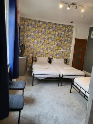two beds in a room with a floral wall at Tulip Hotel Blackpool in Blackpool