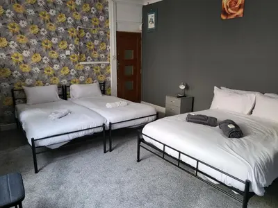 a room with two beds and a wall with flowers at Tulip Hotel Blackpool in Blackpool
