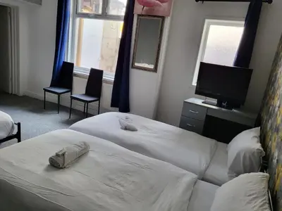 a bedroom with two beds and a television and two chairs at Tulip Hotel Blackpool in Blackpool