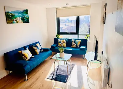 a living room with a blue couch and a tv at Claire Stay Apartment in Liverpool