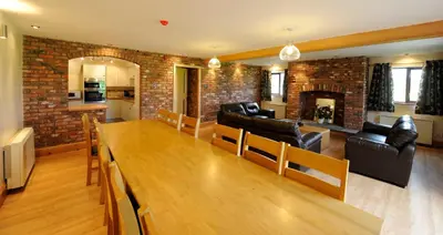 a living room with a wooden table and a brick wall at Marsh Farm Hall in Great Eccleston