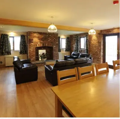 a living room with leather couches and a fireplace at Marsh Farm Hall in Great Eccleston