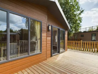 a house with a wooden deck with windows at Bittern Lodge: 3BD Retreat in South Lakeland Park in Borwick