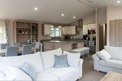 a living room with a white couch and a kitchen at Bittern Lodge: 3BD Retreat in South Lakeland Park in Borwick